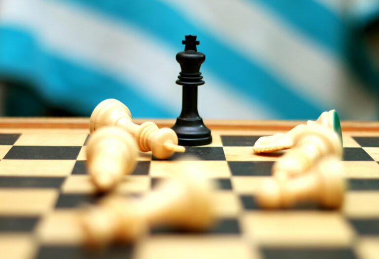 A chess board showing pieces knocked over with one remaining standing